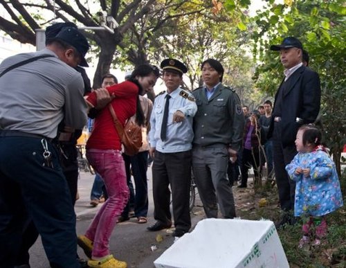 城管与女小贩发生冲突后，女小贩被警方强行带走，她的孩子在一旁放声大哭。南都记者 黎湛均 摄